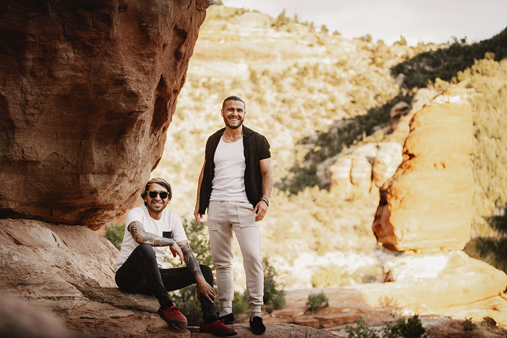 baltic-and-birch-1000x667 Baltic and Birch stand and sit facing the camera. They are next to a large boulder in a scenic exterior.